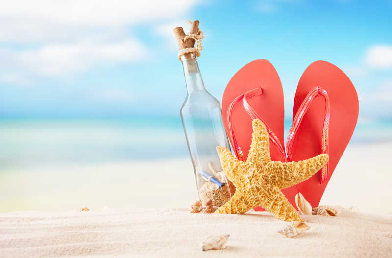 海滩上红色凉鞋海星和漂流瓶