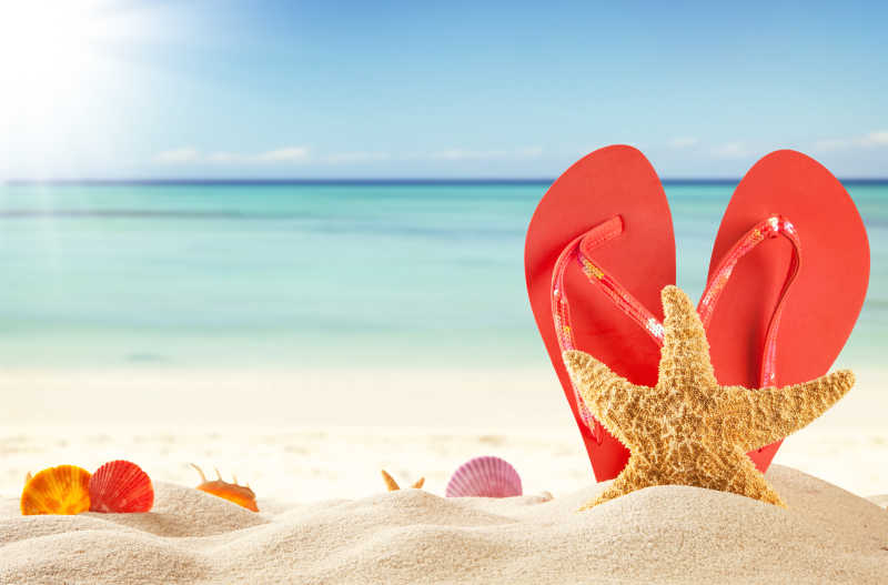 夏日海滩上红色凉鞋和贝壳