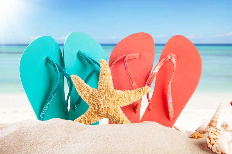 在夏日的海滩上有两双凉鞋和海星贝壳