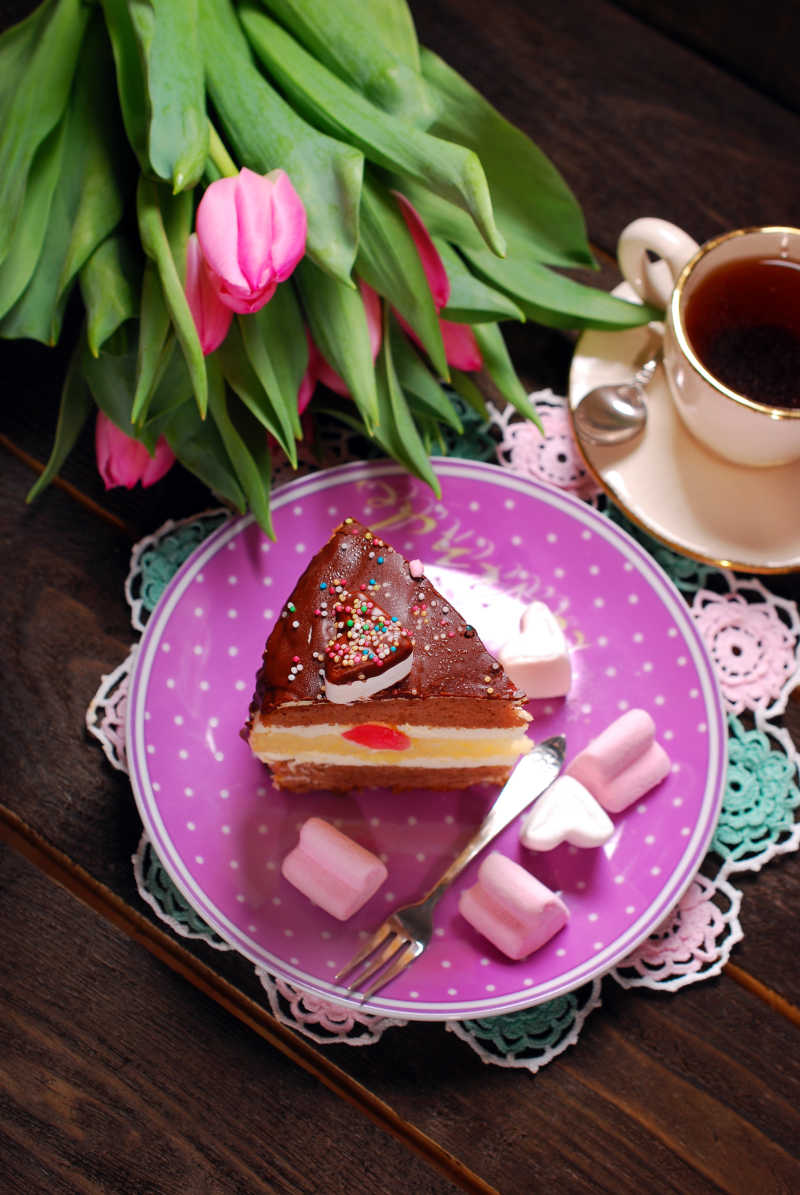 切块放在盘子里的情人节蛋糕旁边还有粉色郁金香