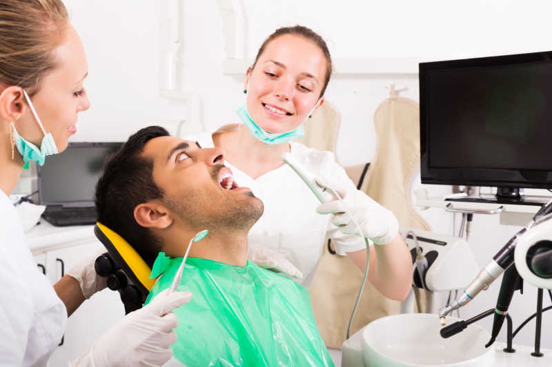 年轻牙科医生帮男性患者检查牙齿