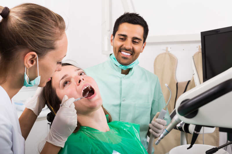 牙科医生认真的诊断女性患者的口腔健康