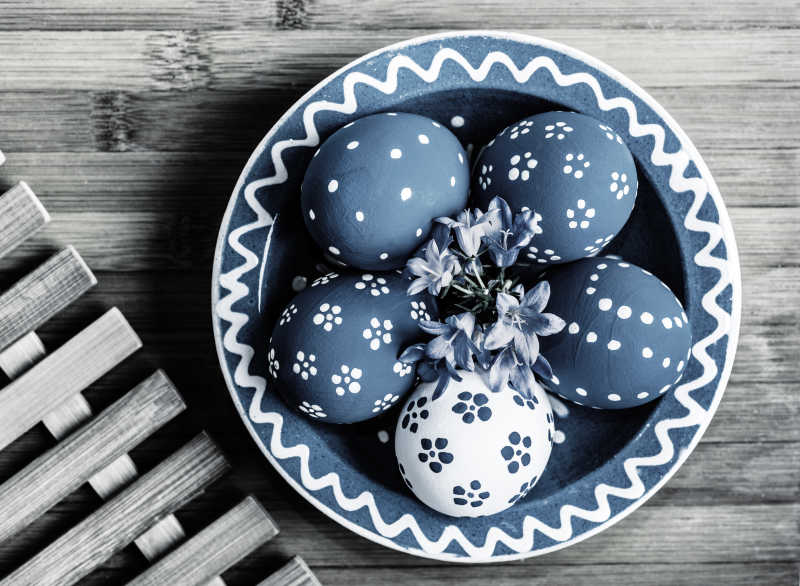 绿松石复活节彩蛋与木制背景上的陶瓷碗匹配特写