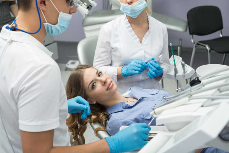 两个牙医帮美女检查牙齿特写