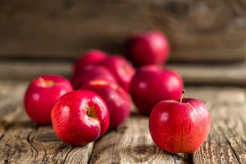 在木质桌子上散落的红苹果