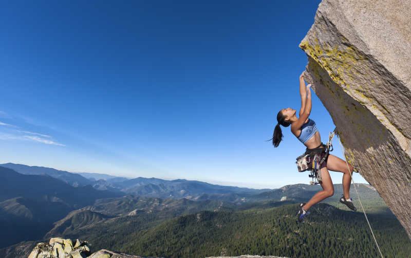 女攀岩者抓在悬崖边上做极限挑战
