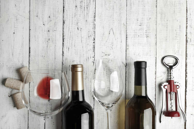 在木质桌板上的葡萄酒瓶开瓶器和酒杯