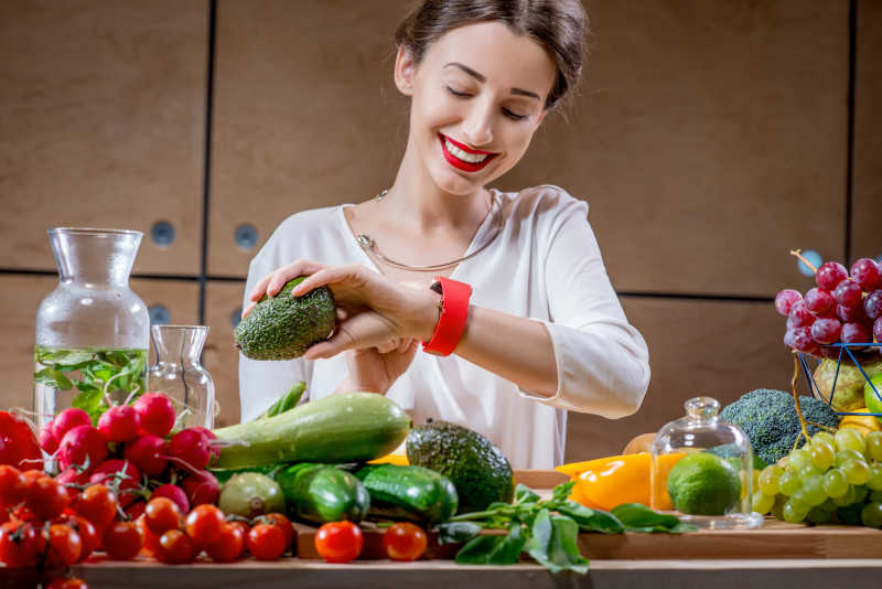 女人面前的餐桌上装满了水果和蔬菜