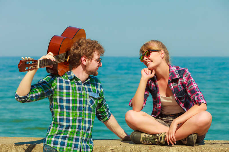 海边约会给女朋友弹吉他的年轻人