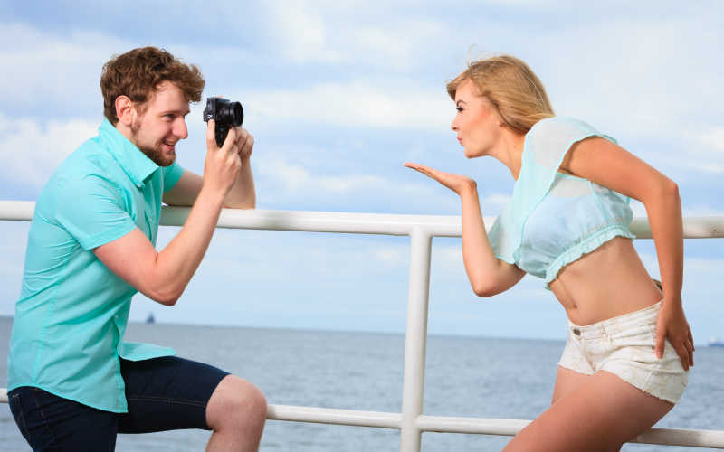 相爱的年轻情侣海边码头上拍照