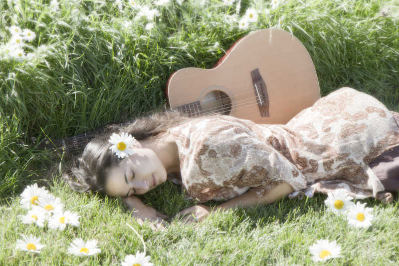 草地上带着吉他的漂亮女孩