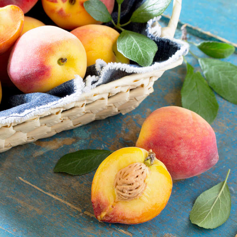 在老式木桌上的柳条筐里收获新鲜成熟的桃子