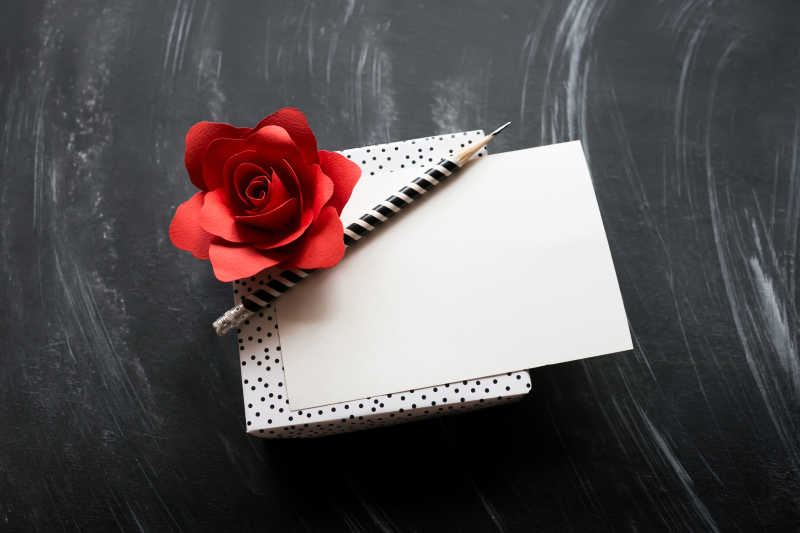 礼品盒上铅笔卡片和红玫瑰纸花