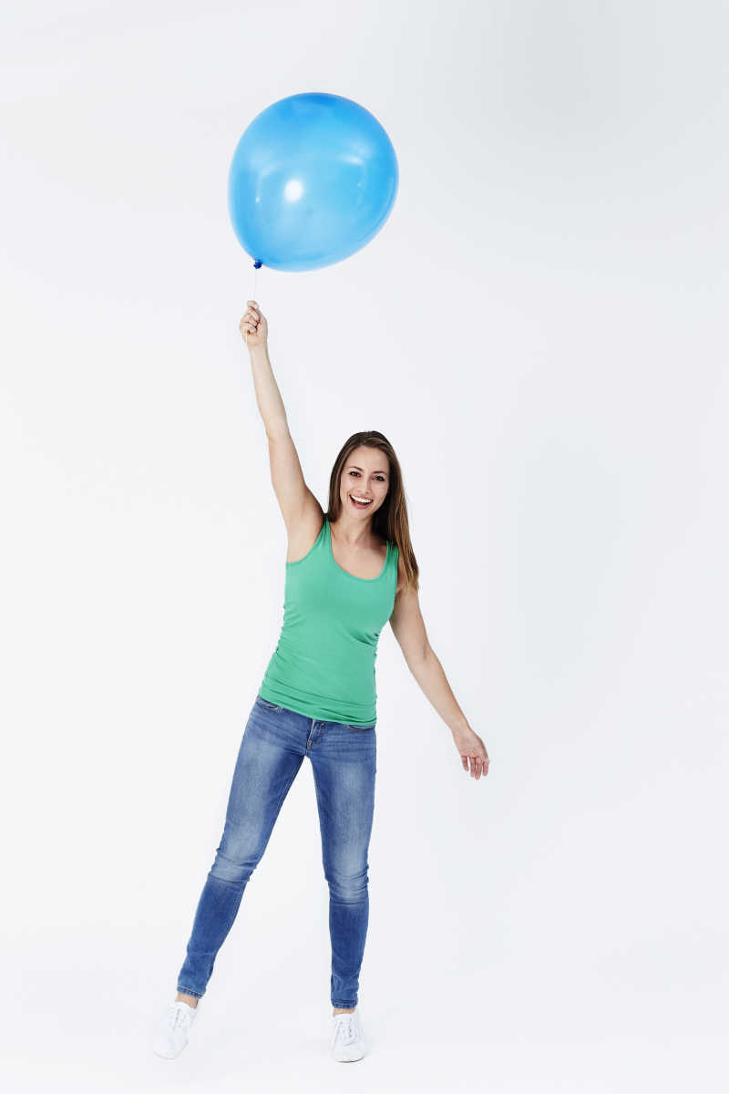 拉着蓝色气球的快乐的美女