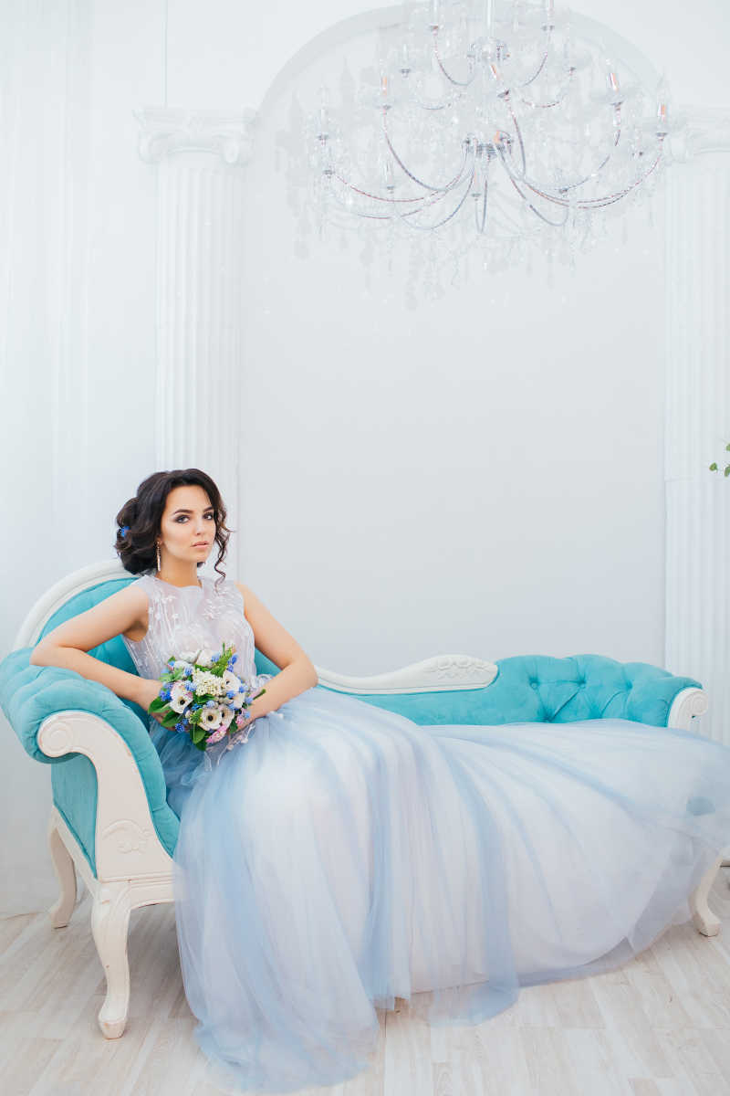 沙发上穿蓝色婚纱的美丽新娘新娘