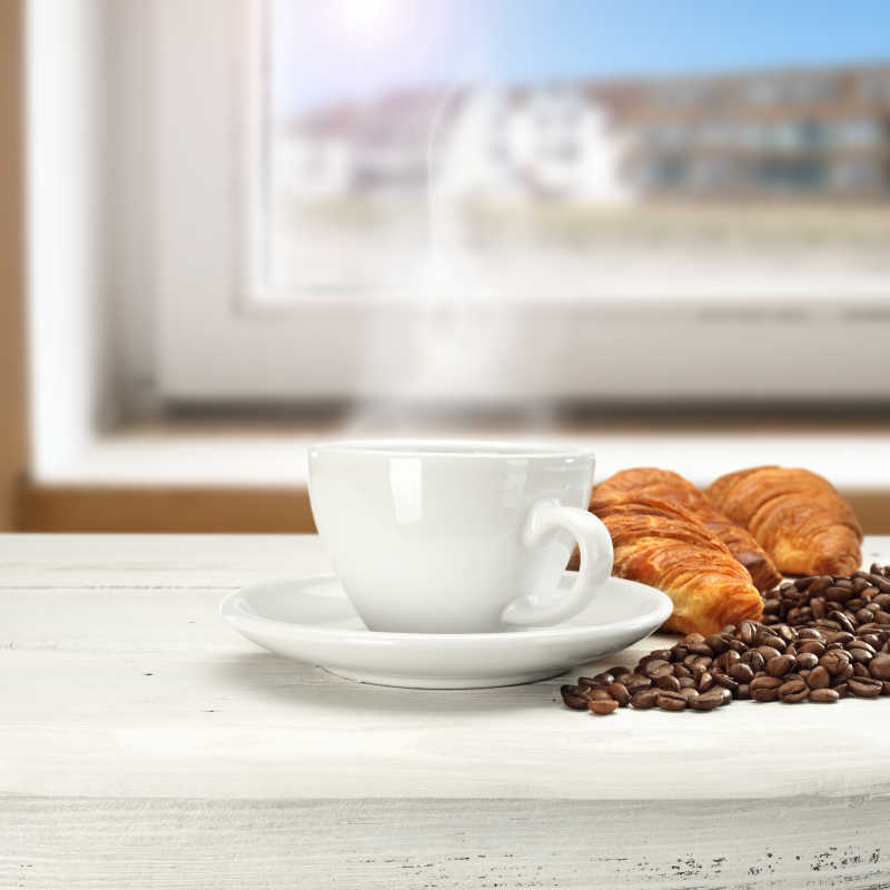 白色咖啡杯里的热咖啡咖啡豆和羊角包