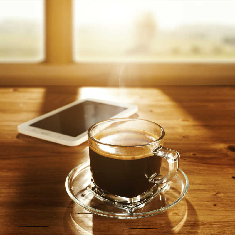 透明咖啡杯里的热咖啡和智能手机