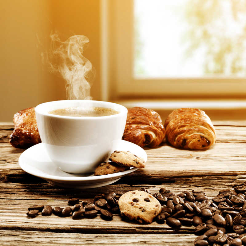 木制桌面上的热咖啡咖啡豆和羊角包