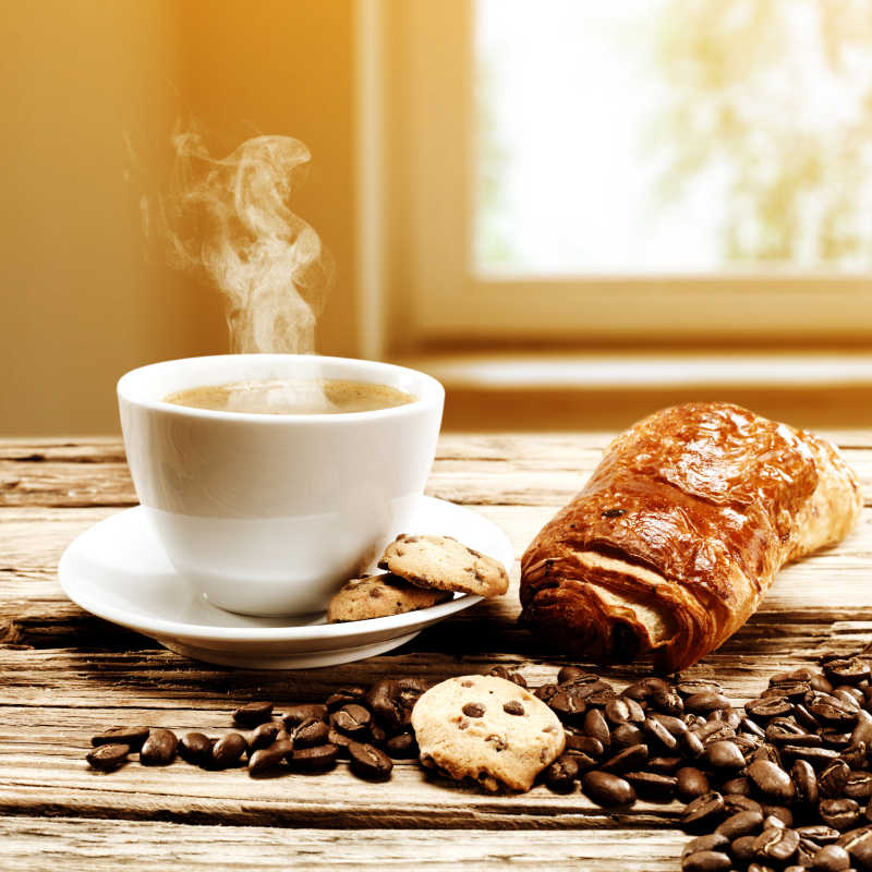 木制餐桌上的热咖啡和咖啡豆面包