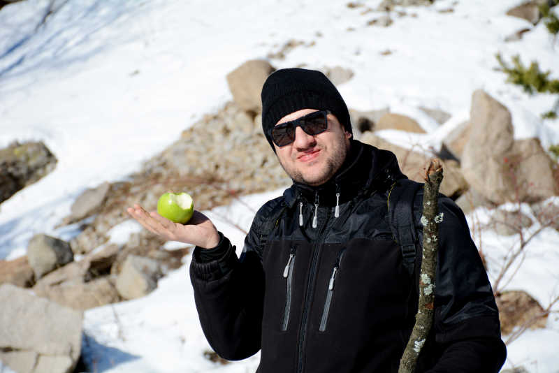在冬天的山上年轻人吃青苹果