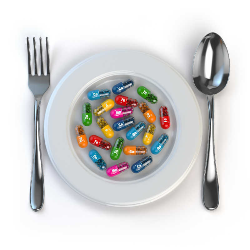 饮食药片和维生素在盘子上用勺子和叉子