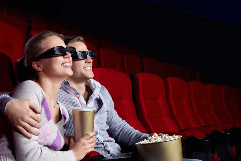 在电影院戴着3D眼镜看电影的情侣