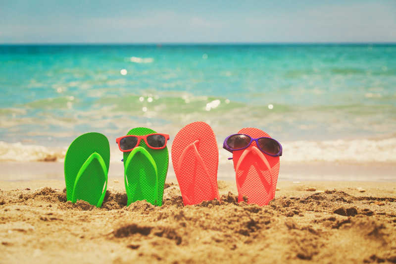 插在沙滩的两双拖鞋上放着墨镜