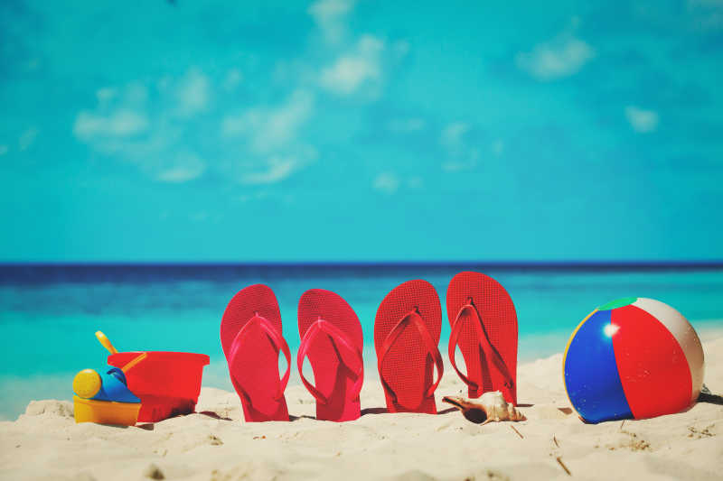 插在沙滩上的两双红色拖鞋和玩具