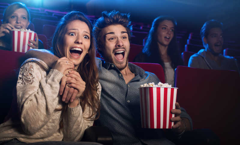在电影院看恐怖电影的年轻夫妇