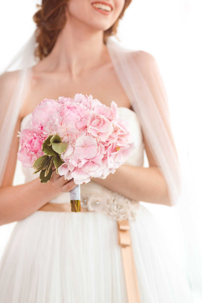穿着婚纱的美女手捧粉色花束