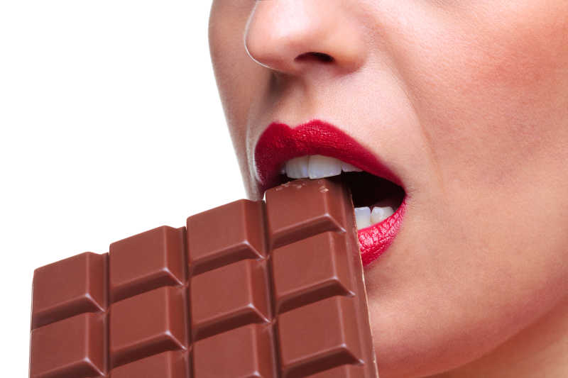 一个红唇女人在咬一大块巧克力