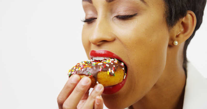 黑人妇女吃巧克力甜甜圈