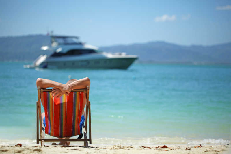海边躺椅上休闲放松的美女在眺望海面上的轮船