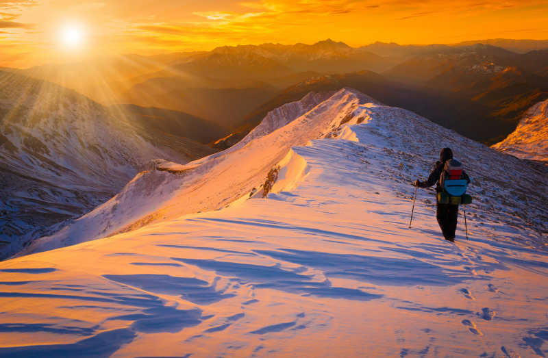 夕阳下雪山上行走的人