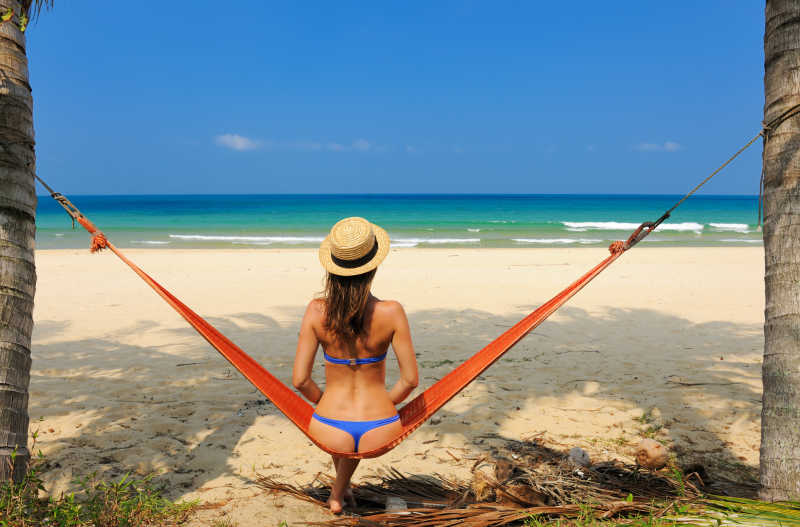 海滩吊床上的坐着的女人看海背景