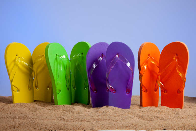 四双彩色拖鞋在海滩上