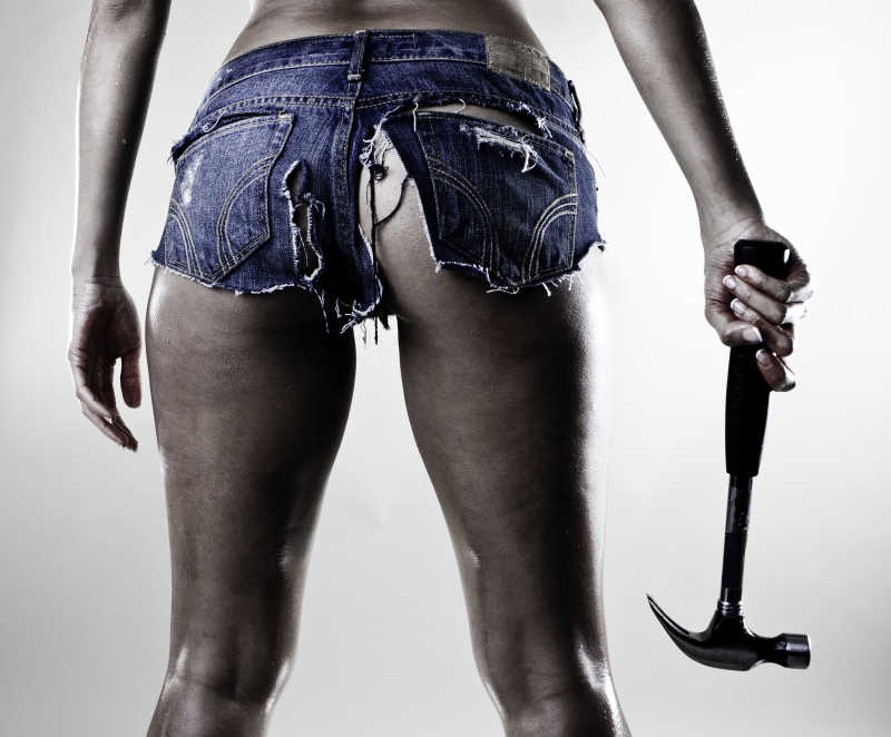 穿着撕裂的短裤拿着锤子的性感女子