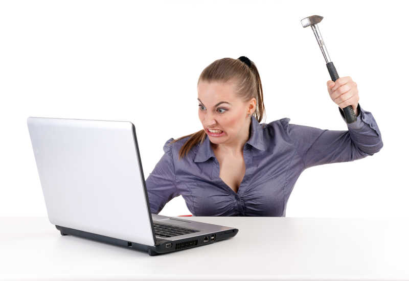 白色背景下拿着斧子砸向笔记本电脑的愤怒的女性