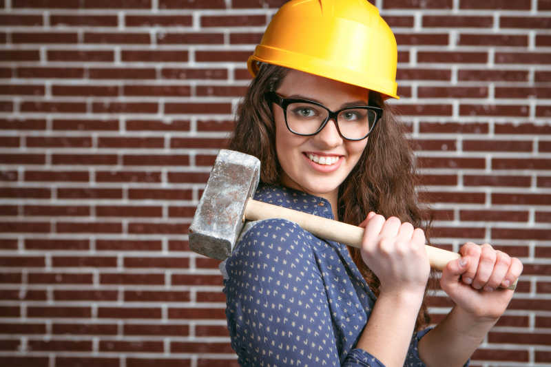 带着安全帽的扛着铁锤的女建筑工人