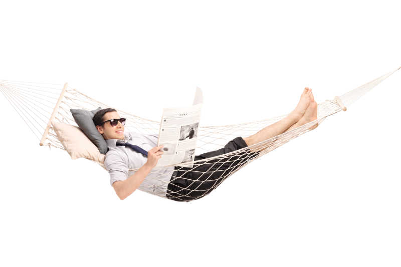 一个男人躺在舒适的吊床上看报