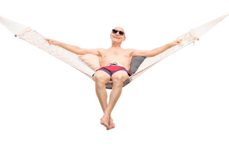 一个穿着红色泳裤的老人躺在吊床上放松