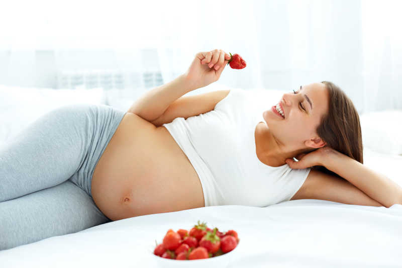 怀孕的女人在家吃草莓