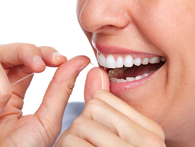 女人在使用牙线清洁牙齿