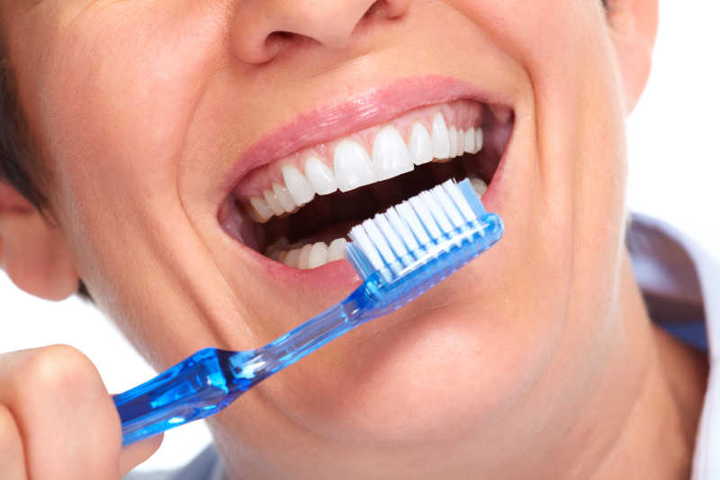 女人在展示牙刷与洁白的牙齿