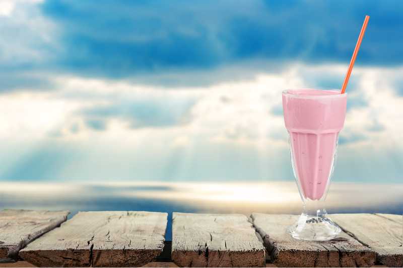 在自然背景下一杯粉色的奶昔特写
