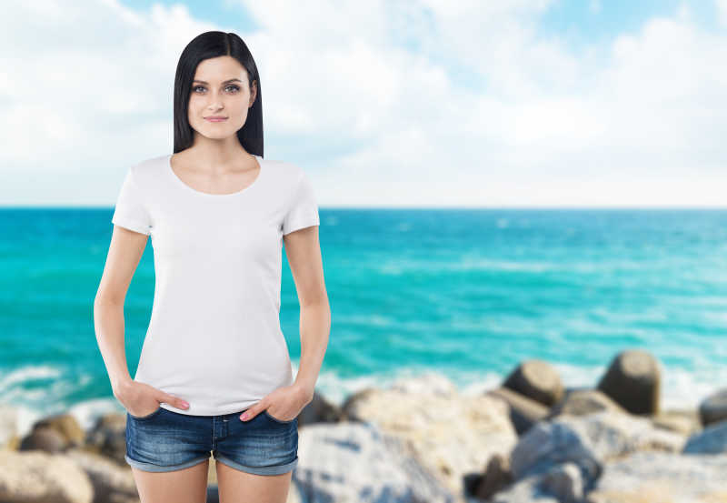 海边背景的年轻女子身穿白色体恤
