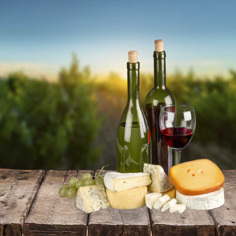 木板上放有红酒奶酪以及葡萄