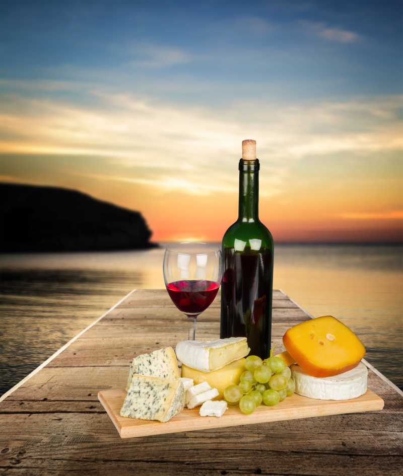 木板上放有红酒葡萄和奶酪