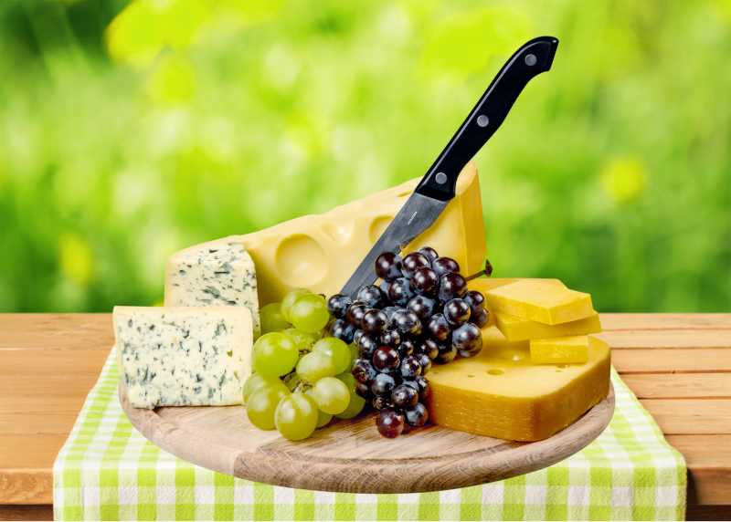 绿色桌布上的干奶酪葡萄及刀具