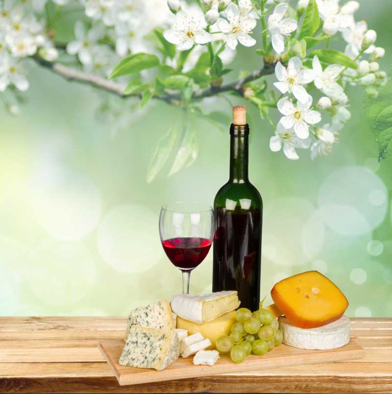 白色花朵背景下的红酒奶酪以及葡萄等食物